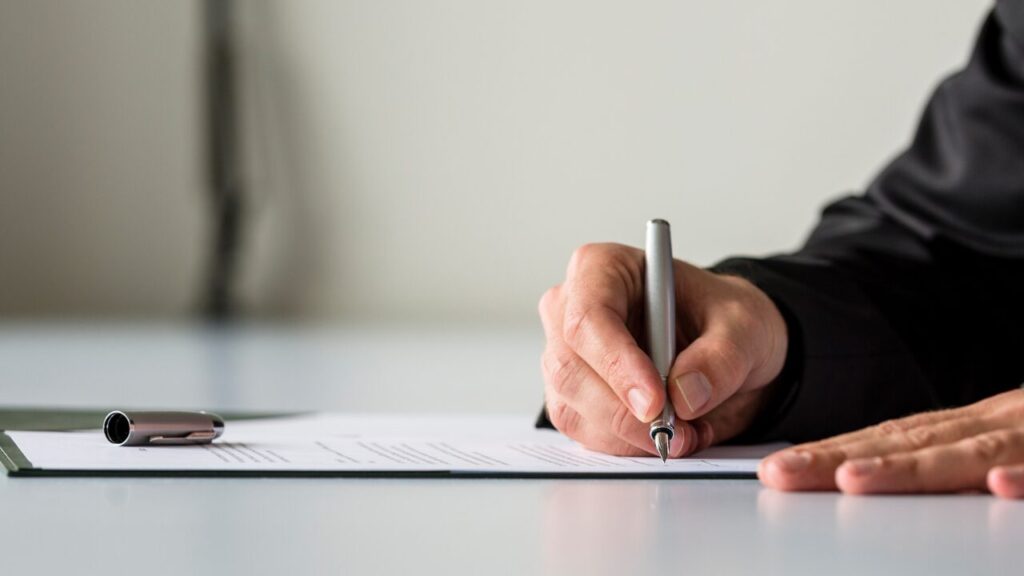 書類にサインしようとしている人の手元の画像（契約のイメージ）